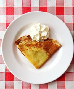 High angle view of crepe and whipped cream in plate on table