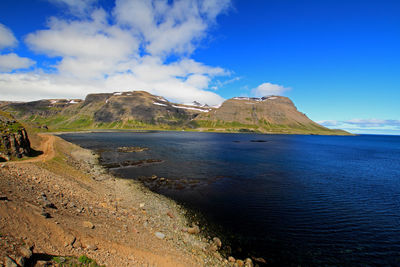 Scenic view of sea and mountains against blue sky