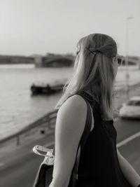 Side view of woman looking away while standing against sky