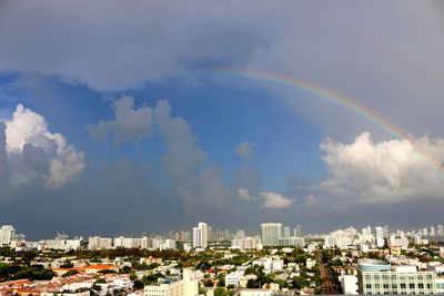 Rainbow over cityscape against sky