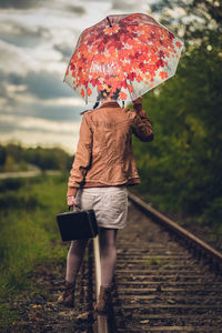 Rear view of woman with umbrella walking on rainy day