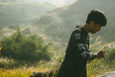 Side view of young man standing on field