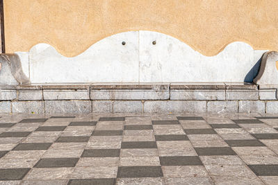 Ancient stone seat on a checkerboard floor