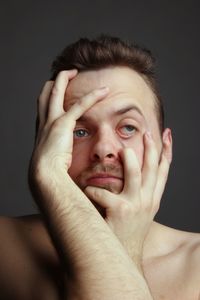 Portrait of shirtless young man against black background