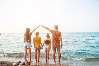 People standing on beach by sea against sky