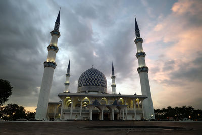Low angle view of mosque against cloudy sky during sunset