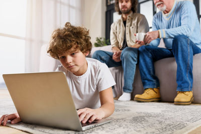 Boy using laptop while men sitting in background