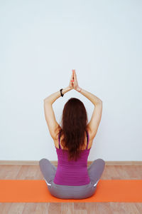 Rear view of woman sitting on wall