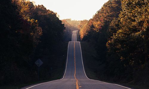 Road amidst trees against sky during autumn