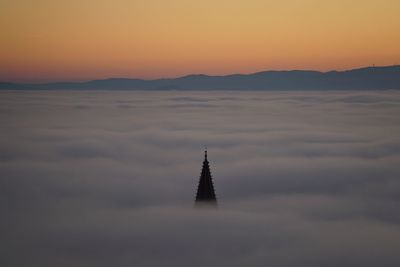 Aerial view of church spire in fog at sunset