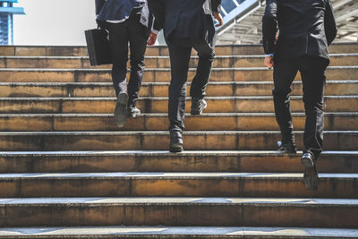 Low section of businessmen climbing on steps