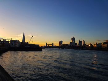 Sea by buildings against clear sky during sunset