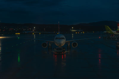 Illuminated airplane on tarmac at night