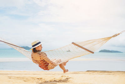 Woman with umbrella on beach against sky