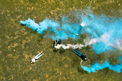 High angle view of people with smoke bombs lying down on field
