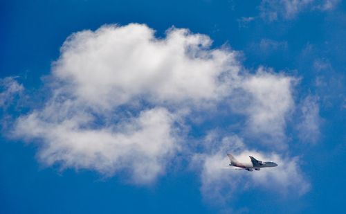 Low angle view of airplane flying against blue sky