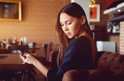 Side view of young woman sitting at restaurant