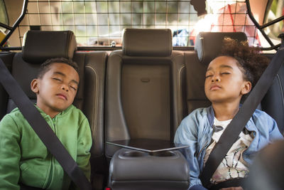 Tired siblings sleeping in electric car