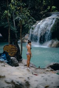 Full length of woman standing by waterfall