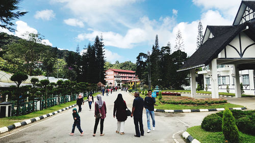 People walking by building against sky