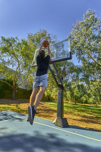 Rear view of young man playing basketball at park