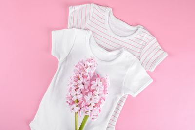 Two cotton baby girl bodysuit with pink hyacinth flowers flat lay layout on pink background