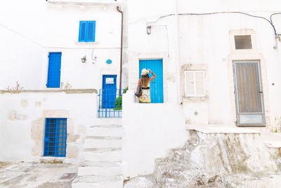 Woman looking at blue door of white apartment building