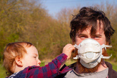 Father with baby trying to remove his face mask