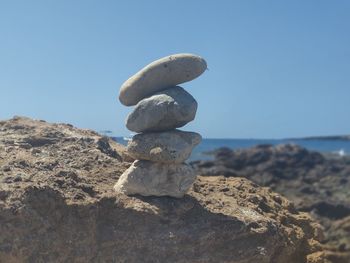 Stack of stones on beach against clear blue sky