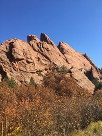 Low angle view of rock formation against clear blue sky