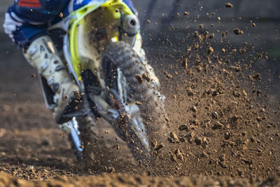 Low section of man riding motorcycle in mud