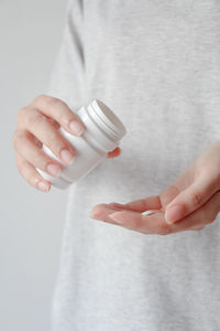 Midsection of woman holding bottle against white background