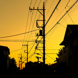 Low angle view of silhouette electricity pylon against sky during sunset