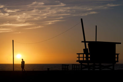 Silhouette man standing on beach against sky during sunset