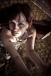 High angle portrait of woman standing by fence