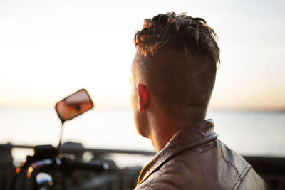 Rear view of motorcyclist looking at sea view during sunset