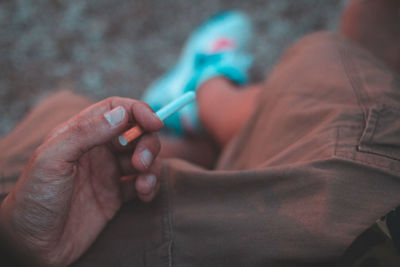 Low section of man holding cigarette