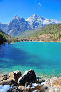 Scenic view of sea by mountains against blue sky