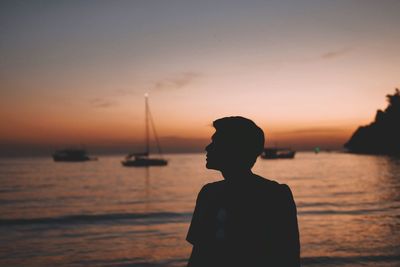 Silhouette man fishing in sea against sunset sky