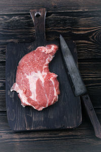 Chopping cutting board with meat and a knife for slicing on the old wooden background with space 