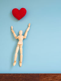 Low angle view of heart shape on table against blue wall