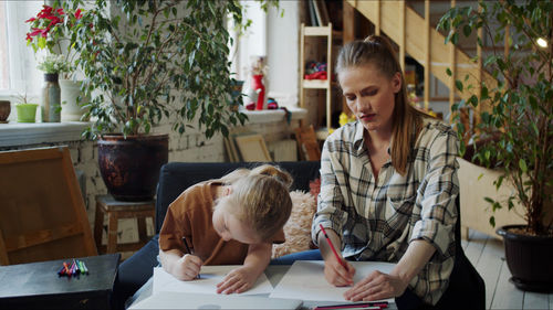 Mother teaching drawing to daughter at home