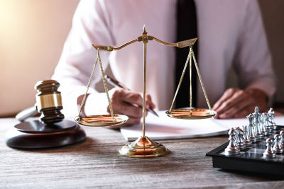 Midsection of lawyer writing on book at office