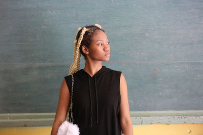 Low angle view of girl looking away while standing against wall