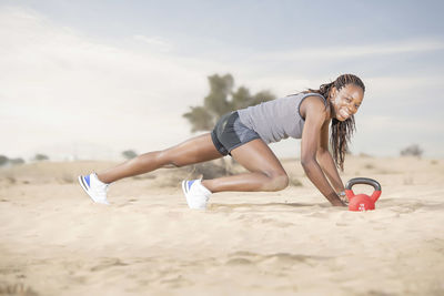 Full length of woman exercising in desert against sky
