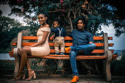 Portrait of woman sitting on bench against trees