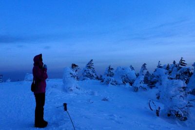 Rear view of woman standing on snow field against sky