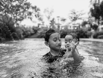 Full length of shirtless boy and woman in swimming pool