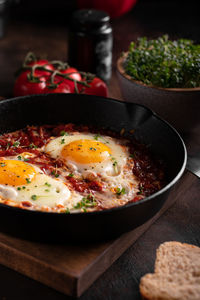 Breakfast with shakshouka and vegetables on a wooden table close up image