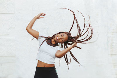 Woman tossing hair while standing against wall